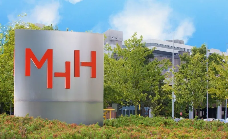 Hannover Medical School campus entrance sign, with the main hospital building behind it